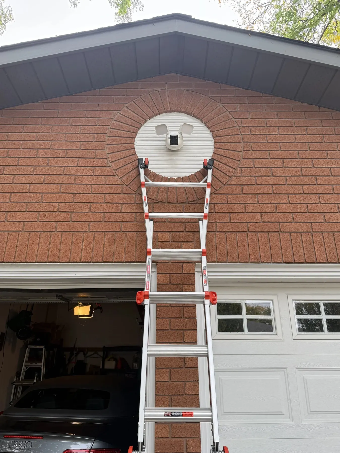 Hutch Security Systems technician ladder set against a brick gable during a camera install