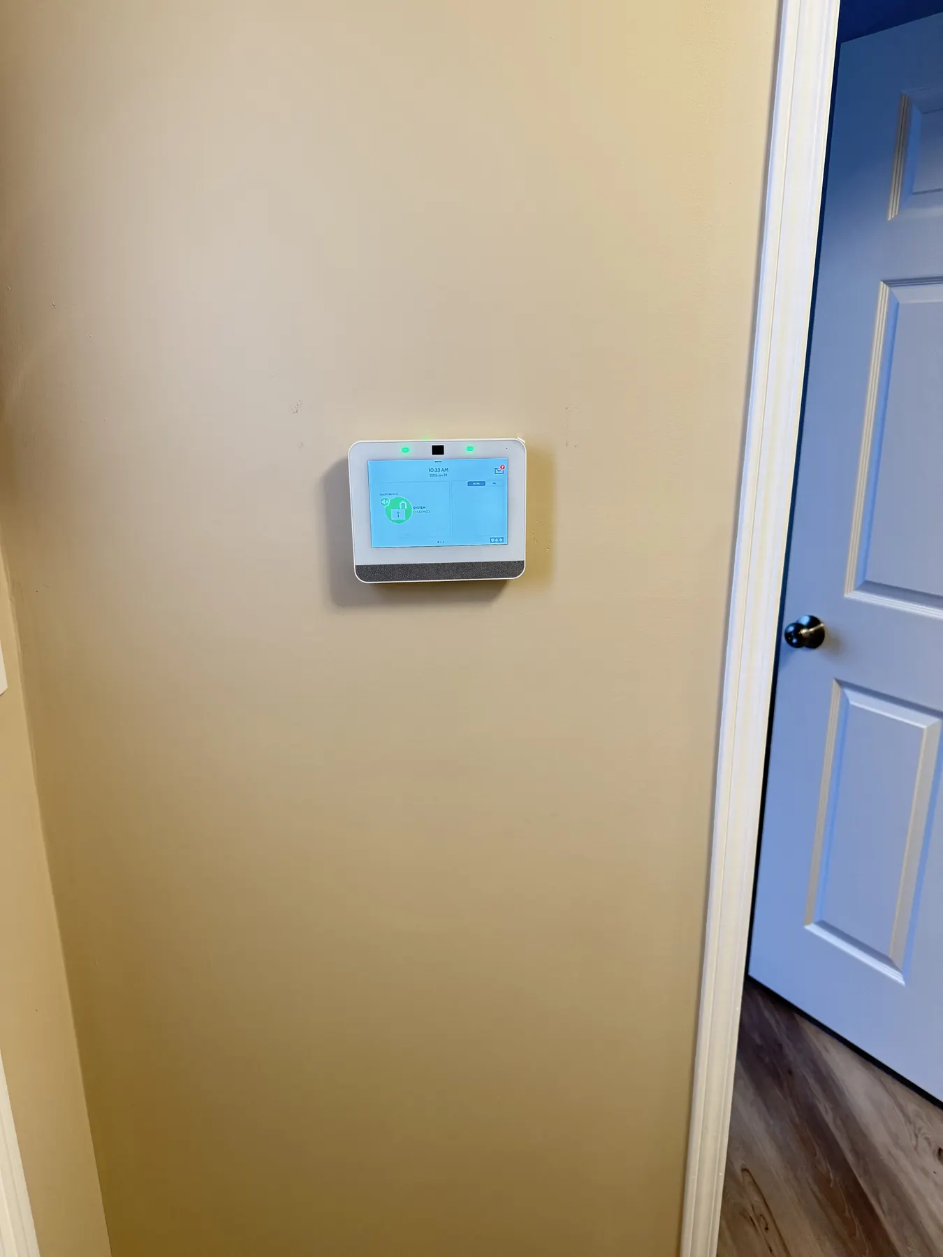 Touchscreen alarm panel on a hallway wall beside an interior door